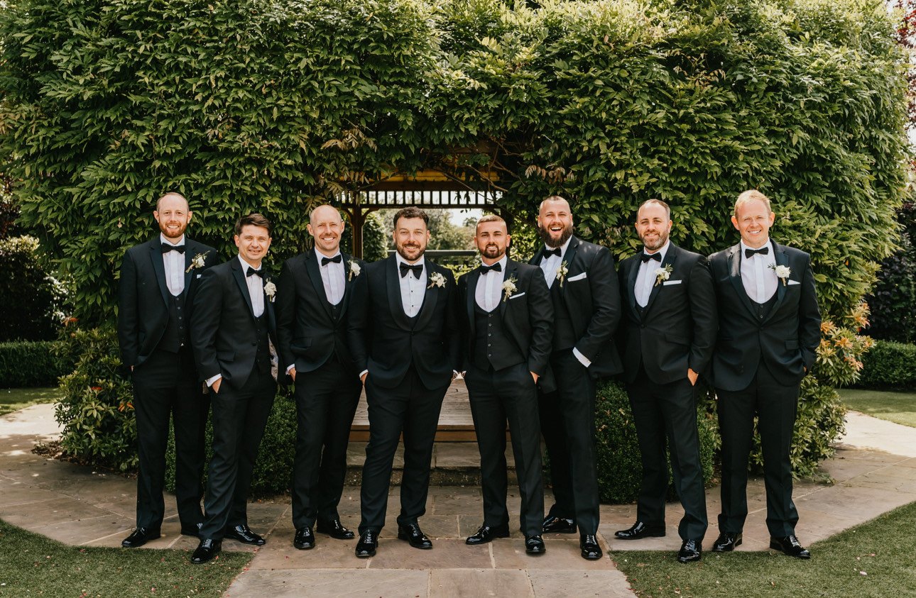 Groom and groomsmen in black tie dinner suits at a wedding